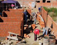 Volunteers on a construction site building a brick house