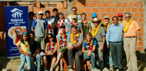 Volunteers and locals posing in front of partially completed house