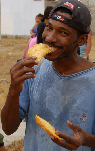 Latino man smiling and eating an empanada