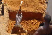 Strong man digging in hard dirt with pick