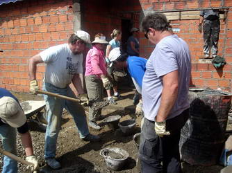 Team members use bucket brigade to deliver cement for beams