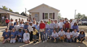 Volunteers posing with President Jimmy Carter in front of new house.