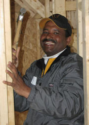 Smiling man with hammer inside house being built
