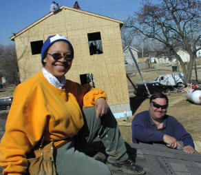 Two volunteers on garage roof in front of house being built